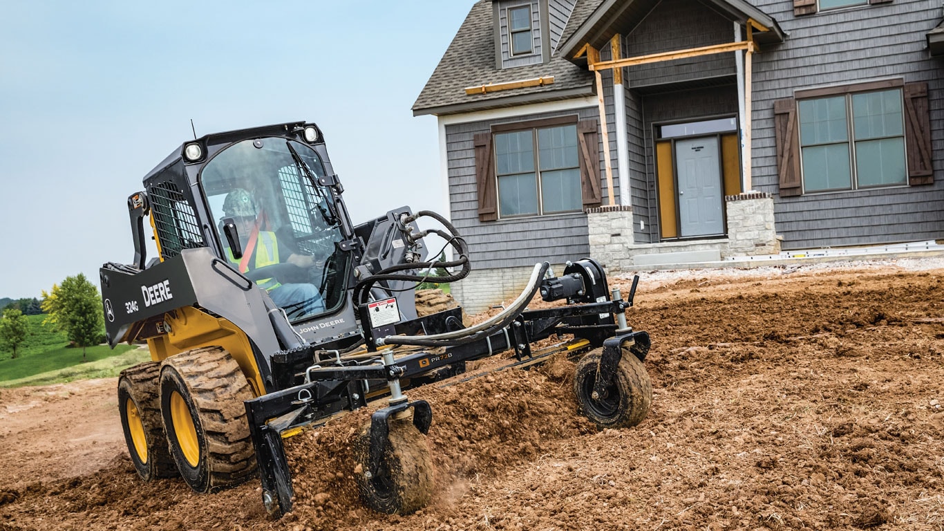 John Deere Skid Steer with Power Rake Attachment at jobsite.